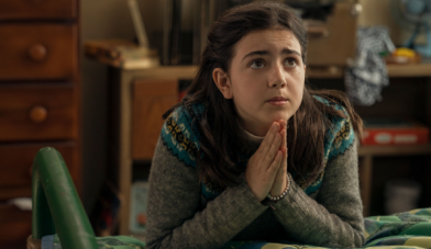 Image of young girl with dark hair praying by her bed