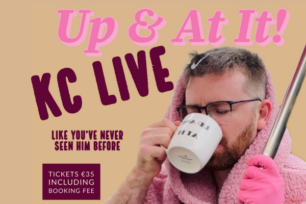 Kieran Corrigan holding a mop and drinking a cup of tea with rubber gloves