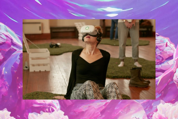 Woman sitting on the floor with a VR headset on and the animation from the visrtual reality landscape visible as the border around her image