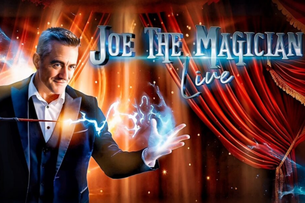 Joe the magician with blue sparks coming from his wand into his other hand on a stage with red curtains
